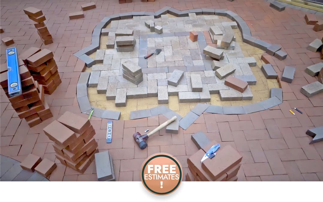 Paver installation project with tools and materials, featuring a "Free Estimates" sign.