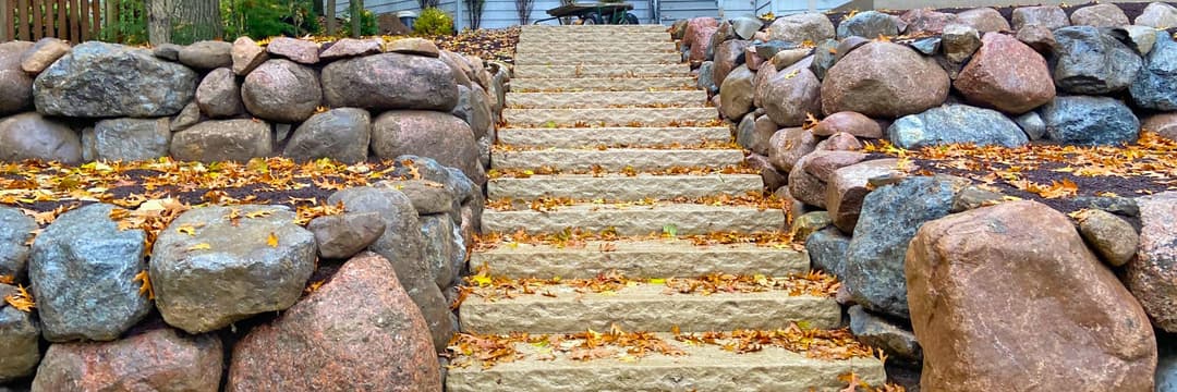 Stone staircase surrounded by rock walls and autumn leaves in a natural setting.
