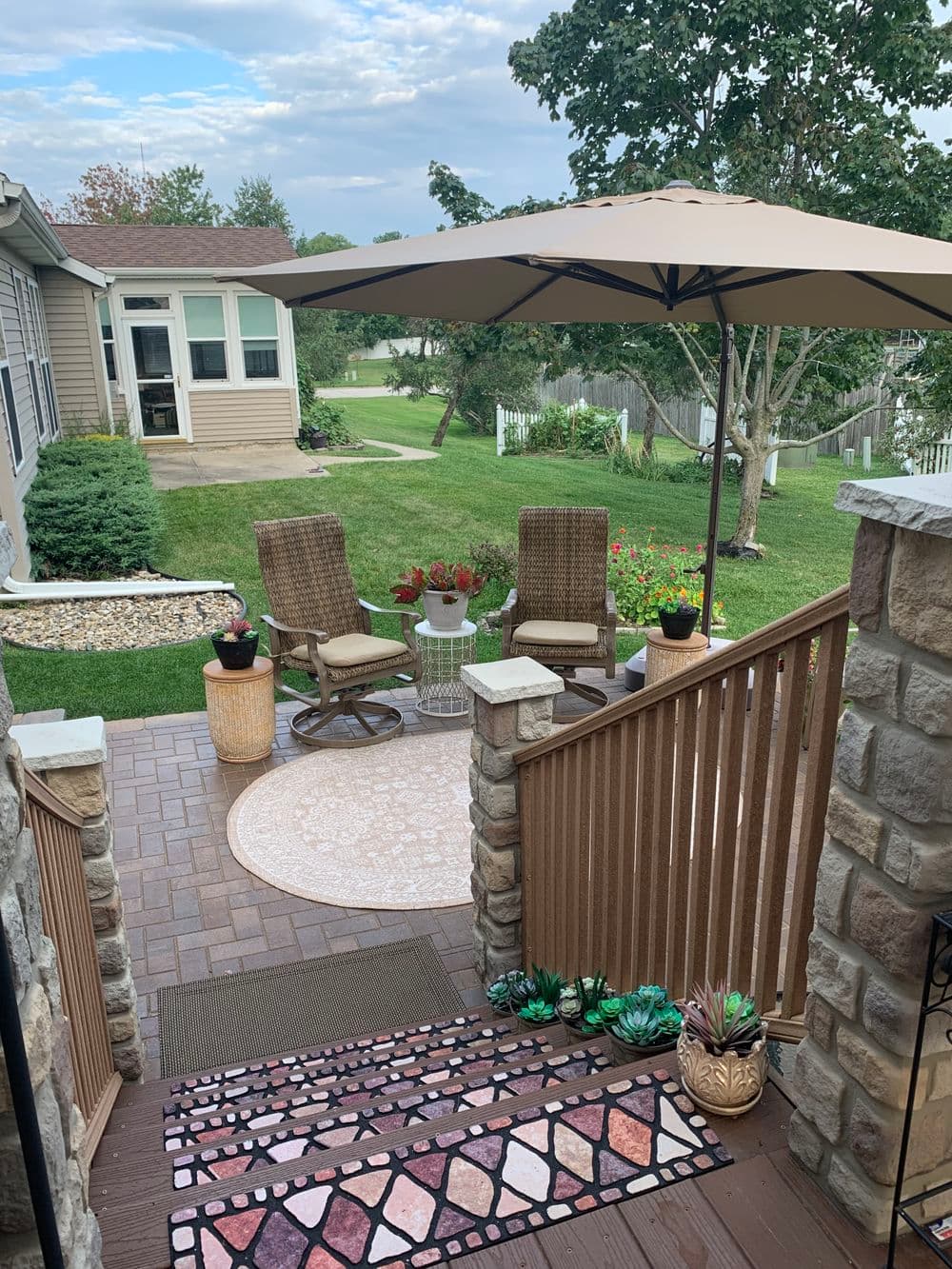 Cozy backyard patio with chairs, umbrella, and flower garden in a serene setting.